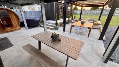 a patio with a wooden table and a couch and a table and chairs at The Mango Shed in Mangakino