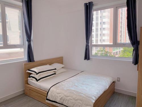a bed in a room with two windows at HomeDubai in Kinh Dinh