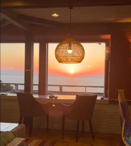 a dining room with a table and chairs and a large window at UMI SORA VILLA 伊豆河津 in Kawazu