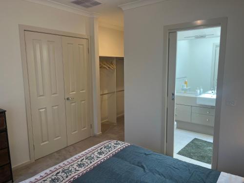 a bedroom with a bed and a bathroom with a sink at Your Leafy Ivanhoe Retreat in Melbourne