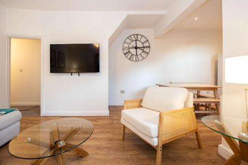 a living room with a white chair and a table at Goulder House- Close To Motorway & CO-OP Live in Manchester