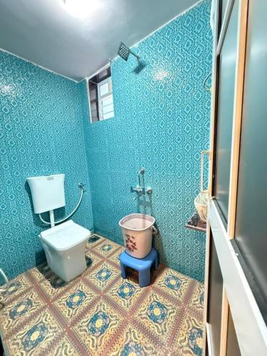 a blue bathroom with a toilet and a bucket at Magic holiday home in Matheran