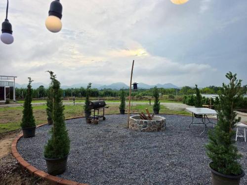 a garden with a grill and a picnic table and trees at LeLaNa Farmstay Camping in Pak Chong