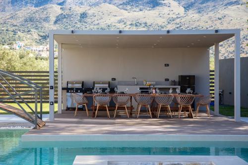 a patio with a table and chairs next to a pool at Elinor Villa - Nature Retreat amidst Mountains & Lake by etouri in Chania