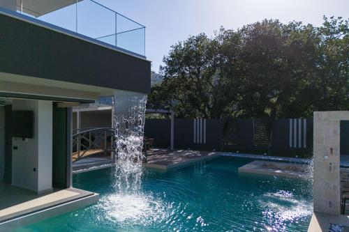 a swimming pool with a water fountain next to a house at Elinor Villa - Nature Retreat amidst Mountains & Lake by etouri in Chania