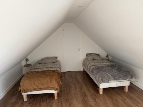 two beds in a attic bedroom with white walls at Ecrin de Lin in Rosnoën