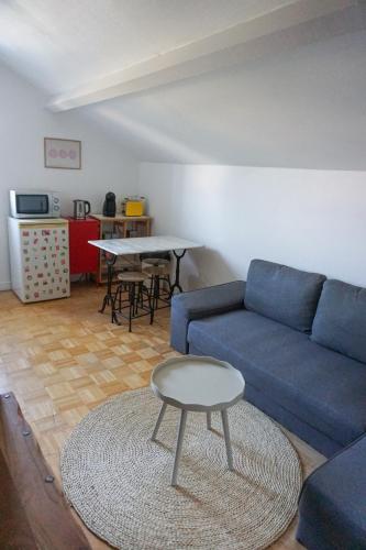 un soggiorno con un divano blu e un tavolo di Appartement confort tout équipé a Montrevel-en-Bresse