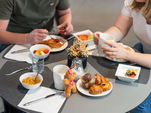 een groep mensen die aan een tafel zitten met eten bij Novotel Suites Colmar Centre in Colmar