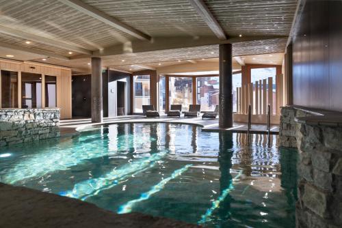 een zwembad in een hotel met een stenen muur bij Résidence l'Oxalys in Val Thorens