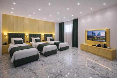 een hotelkamer met drie bedden en een televisie bij Khatai Rest Hotel in Baku