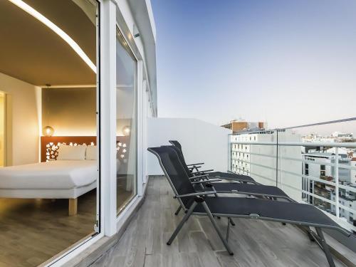 een kamer met een balkon met een bed en stoelen bij Ibis Styles Lisboa Centro Marquês de Pombal in Lissabon