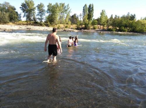 a man standing in the water in a river at Coyunche Cabañas y Camping Laja & San Rosendo in Laja