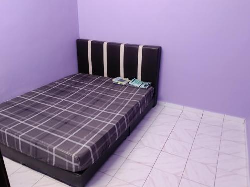 een bed in een kamer met een paarse muur bij Homestay Sayang in Ipoh