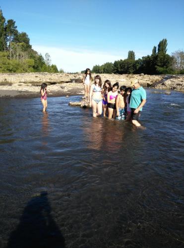 a group of people standing in the water at Coyunche Cabañas y Camping Laja & San Rosendo in Laja