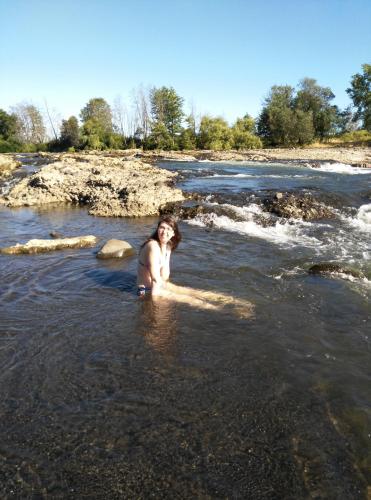a woman standing in the water in a river at Coyunche Cabañas y Camping Laja & San Rosendo in Laja