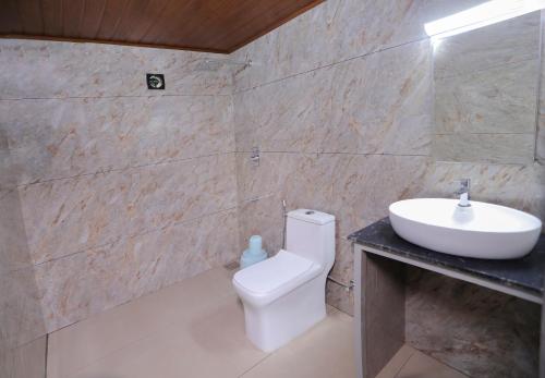 a bathroom with a white toilet and a sink at Rippon Mount Resorts in Meppādi