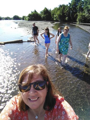 a group of people walking in the water at Coyunche Cabañas y Camping Laja & San Rosendo in Laja