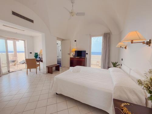 a bedroom with a large bed and a view of the ocean at Mursia Wellness Hotel in Pantelleria