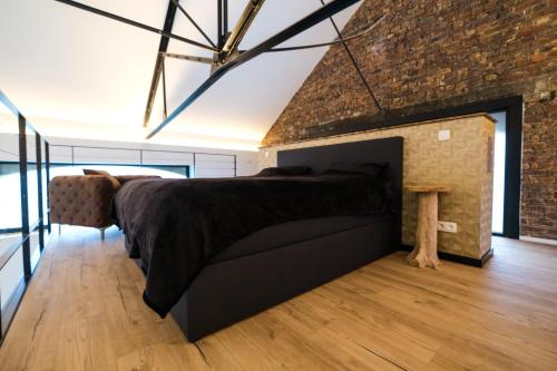 ein Schlafzimmer mit einem großen Bett und einer Backsteinwand in der Unterkunft La Forge in Wanze