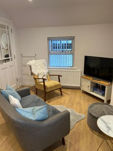 a living room with a couch and a tv at Cosy Loft Apartment in Ballycastle