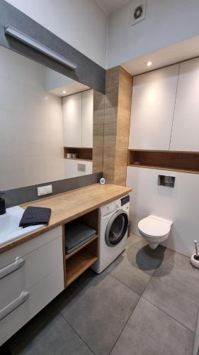 a bathroom with a washing machine and a toilet at Apartament Skarbowa 2 in Leszno