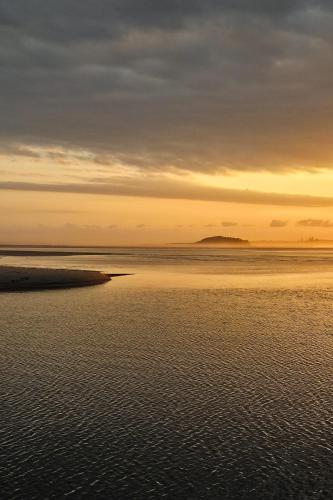 a sunset over the water with the horizon at Harrington Holiday House in Harrington