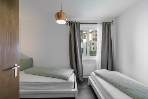 een slaapkamer met twee bedden en een raam bij Chasa Valbernard 4105 in Vulpera