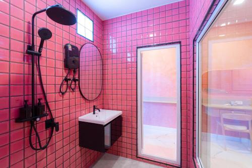un bagno piastrellato rosa con lavandino e specchio di บ้านพวงชมพูเกาะล้าน a Ko Larn