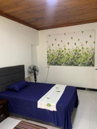 a bedroom with a blue bed and a painting on the wall at JHome in Kurunegala