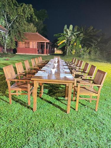 a long wooden table with chairs in the grass at The Thinnai Farm in Jaffna