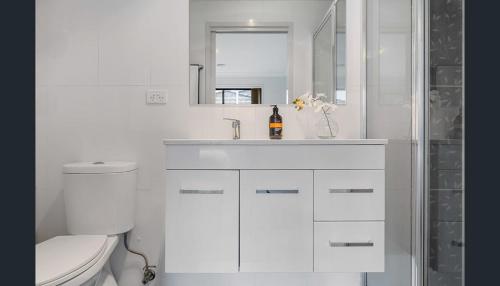 a white bathroom with a toilet and a sink at Four-bedroom house in Gungahlin
