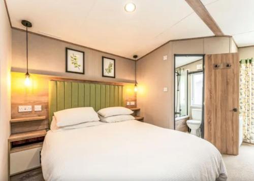 a bedroom with a large white bed and a bathroom at ScottishHighlands in Boat of Garten