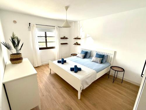 a white bedroom with a bed with blue pillows at Villa Marée La Costa in La Costa