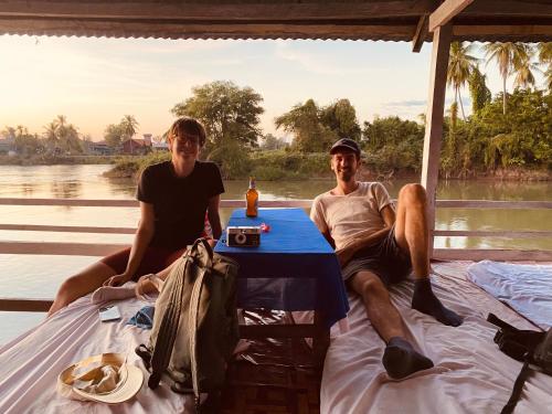 a man and a woman sitting on a table on a boat at souksanh River Bungalow in Along