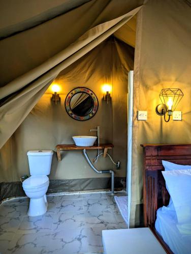 a bathroom with a toilet and a sink in a tent at Olemayian Amboseli Cottages in Amboseli