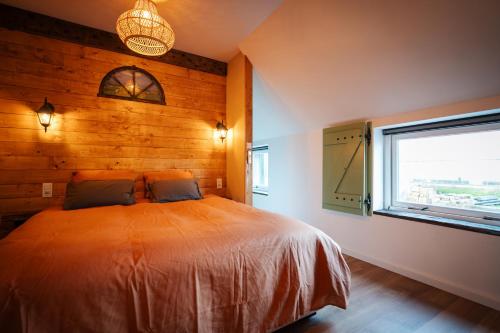 een slaapkamer met een groot bed en een raam bij B&B Lindehoeve Texel in Den Hoorn