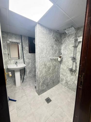 a bathroom with a sink and a shower with a mirror at Grand Stay Abu Dhabi in Abu Dhabi