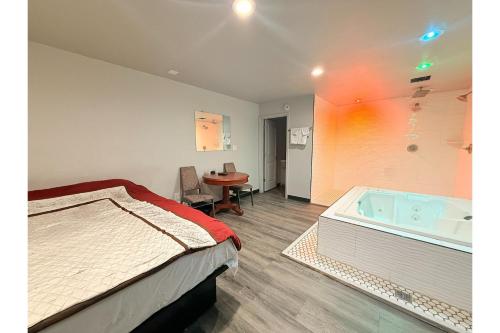 a bedroom with a bed and a bath tub at The Queen B Motel, Detroit-Warren in Warren