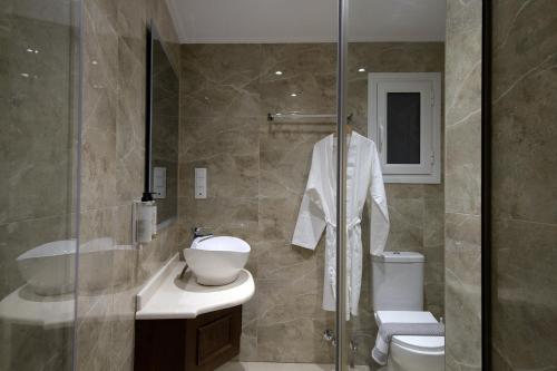 een badkamer met een douche, een toilet en een wastafel bij Hotel Kaiser Bridge in Benitses