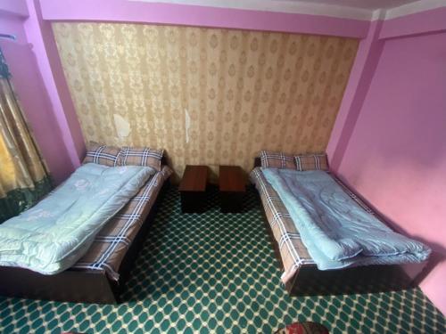 two twin beds in a room with a wall at Hotel tulsi sagar Int'l pvt Ltd in Kathmandu