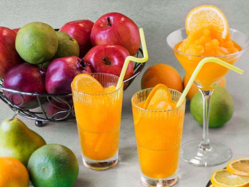 tre bicchieri di succo d'arancia accanto a un cesto di frutta di ibis Styles Dubai Airport Hotel a Dubai