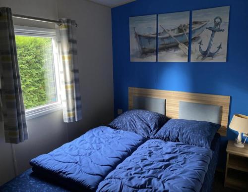 a bedroom with a bed with blue sheets and a window at Beach Resort Kamperland - 1152 in Kamperland