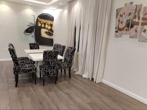 een eetkamer met een tafel en stoelen en een schilderij bij شالية نخلة in Buraydah
