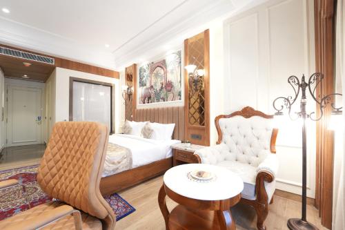 a bedroom with a bed and a chair and a table at Hotel Maharaja Palace Rohtak in Kahrāwar