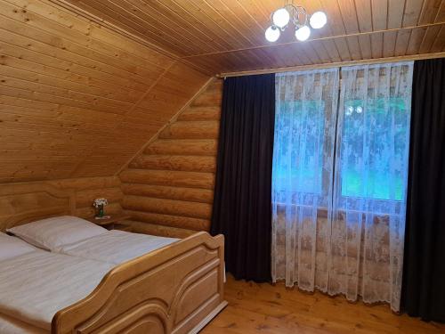 a bedroom with a bed and a large window at Stream House in Lopushnoye