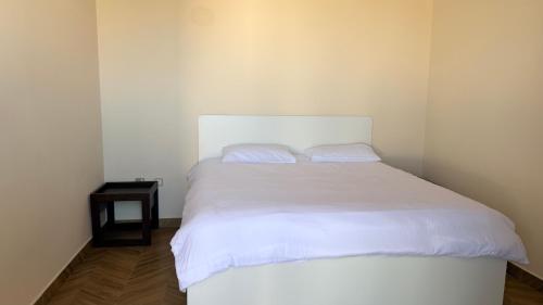 een wit bed met 2 kussens in een kamer bij In The Peaks in Sharīyah