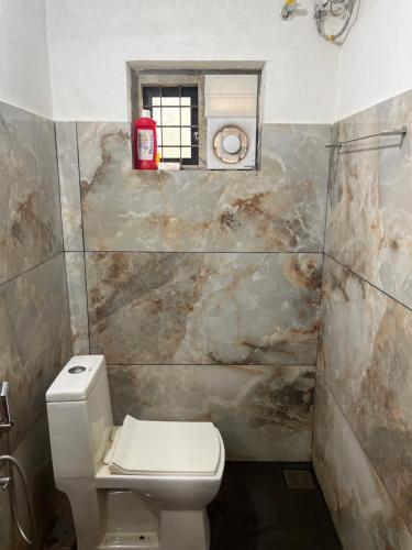 een badkamer met een wit toilet en een raam bij Tulips villa in Mānantoddy