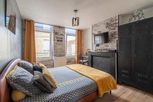 a bedroom with a bed and a desk and a television at comme un air de chez soi in Calais