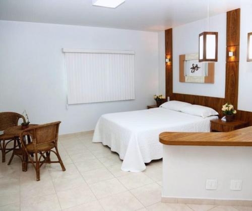 a bedroom with a white bed and a table and a desk at Monte Castro Executive Hotel in Araguari
