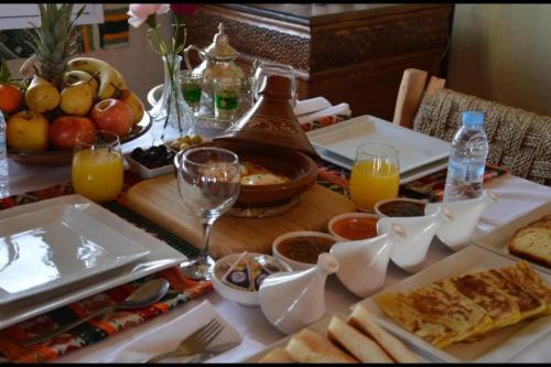 een tafel met eten en glazen sinaasappelsap bij Chegaga Infinite Dunes Luxury Desert Camp in Mhamid